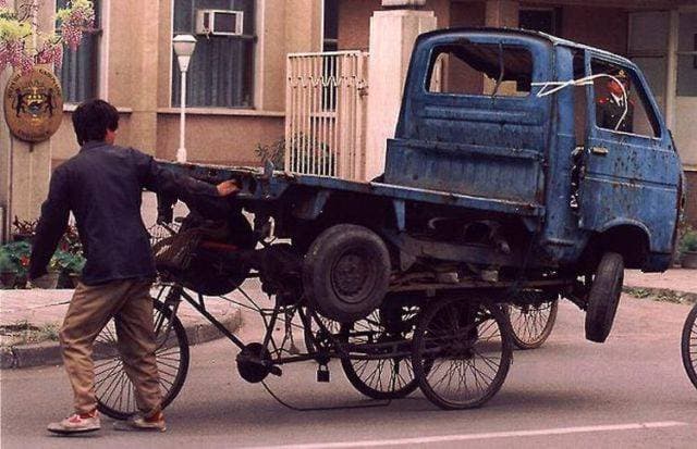 This Person, Who Is Inexplicably Trying To Balance A Car On A Bike