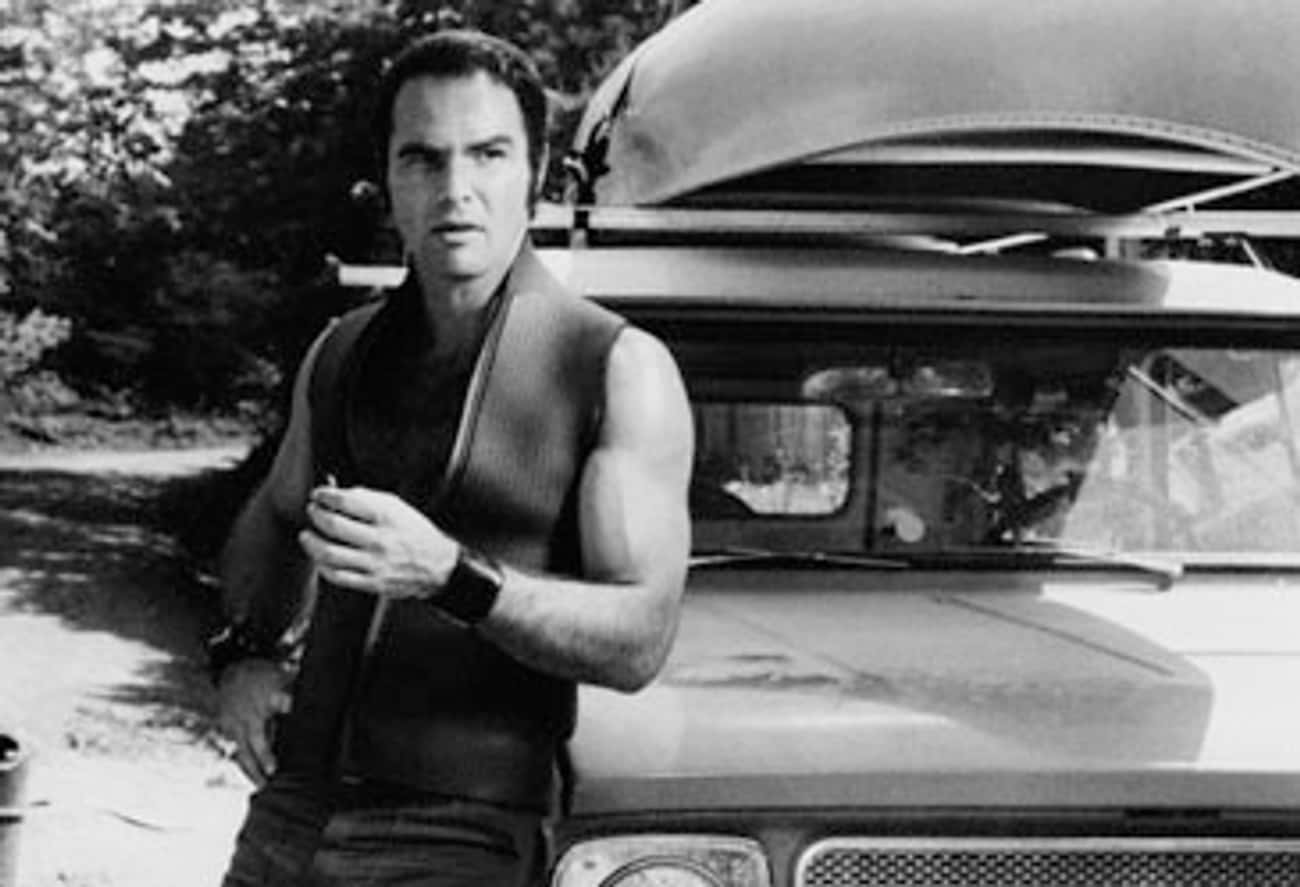 Young Burt Reynolds in a Sleeveless Vest Leaning Against a Car