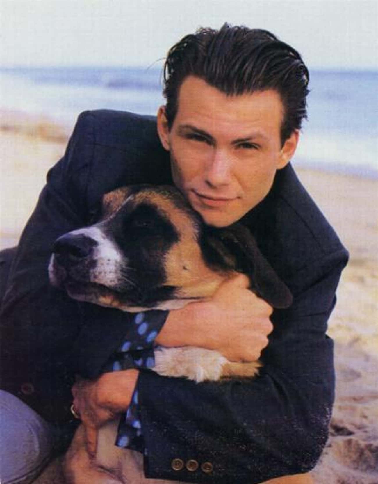 Young Christian Slater in Black Sports Jacket Holding Dog