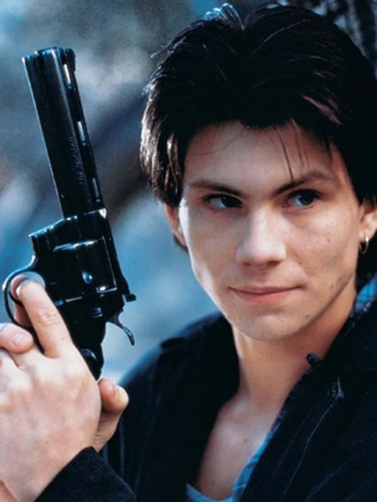 Young Christian Slater in Black Jacket Holding Gun