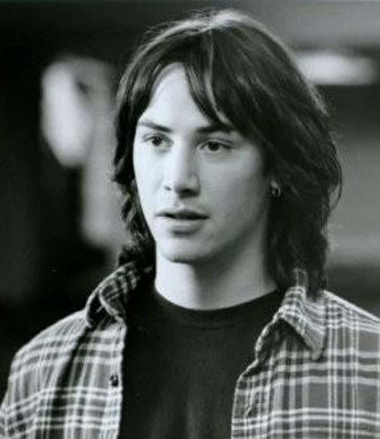 Young Keanu Reeves with Long Hair in Black T-Shirt and Patterned Buttondown Shirt