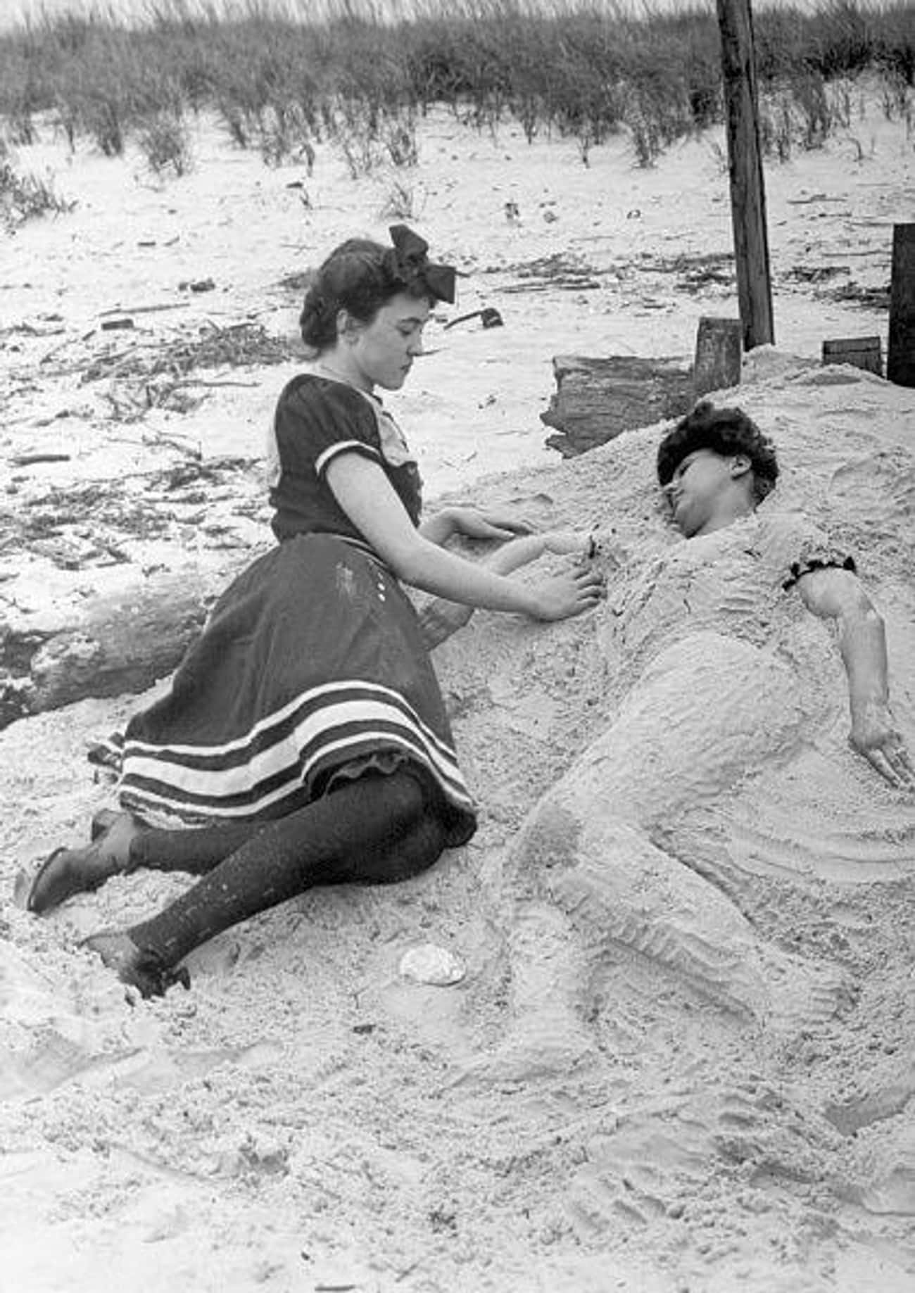 Two Women Participating In The Timeless Tradition Of Burying Your Friend In The Sand On A Beach On Coney Island
